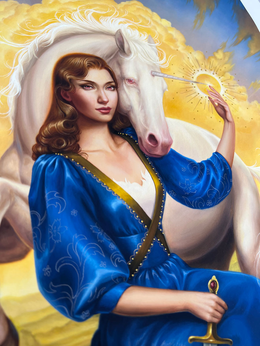 A serene scene inspired by "Lady and the Unicorn" shows a woman in a flowing blue dress beside a white unicorn, gently touching its glowing horn. A magical Allison Reimold hand embellished print, bathed in golden light.