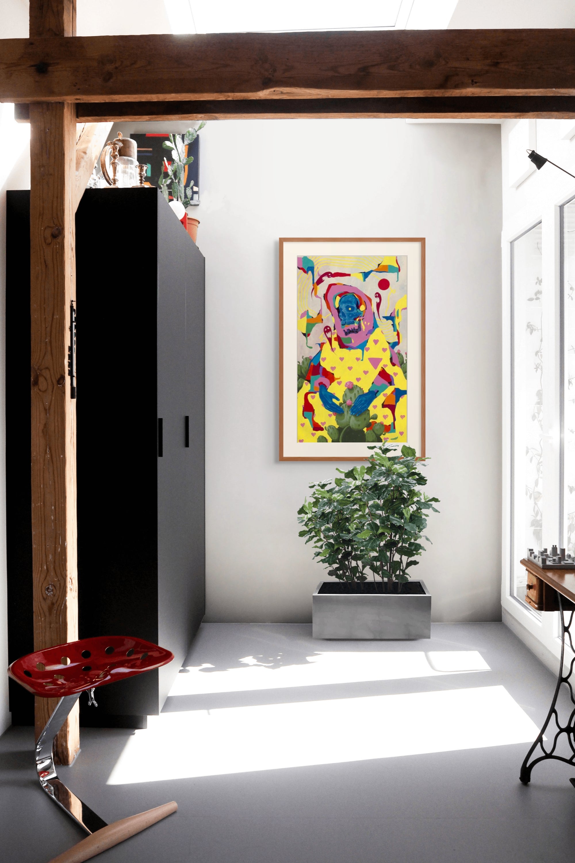 A modern, sunlit interior features "What Doesn't Kill Us" by Anthony Hurd—a signed, numbered abstract dog painting—on a white wall, above a green potted plant, sleek black cabinet, red sculptural stool, and framed by wooden beams.