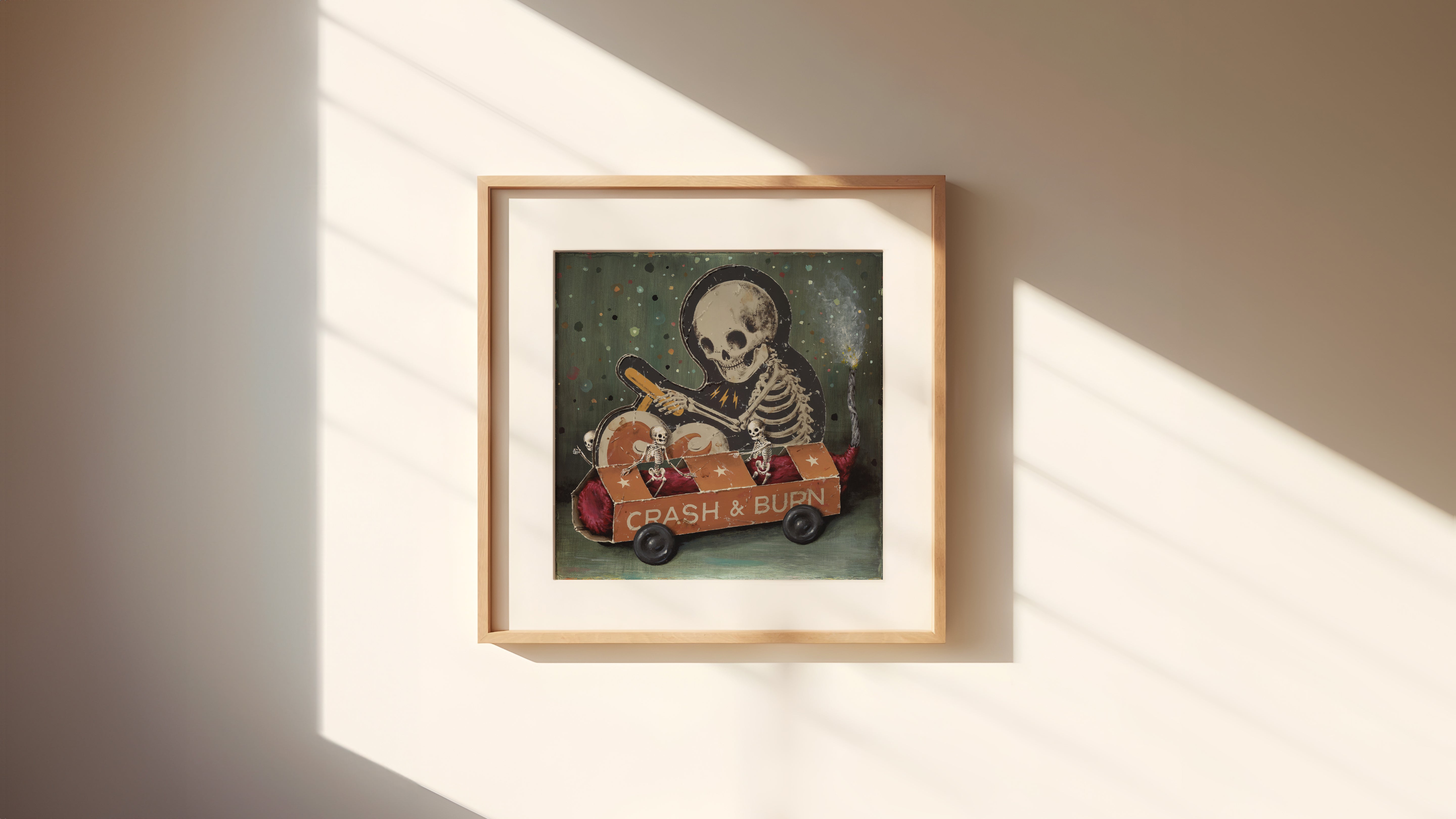 Crash & Burn" by Jason Limon is a framed archival pigment print showing a skeleton driving a red car with the text "CRASH & BURN," holding a bat, hanging on a wall with sunlight and shadows playing across it.
