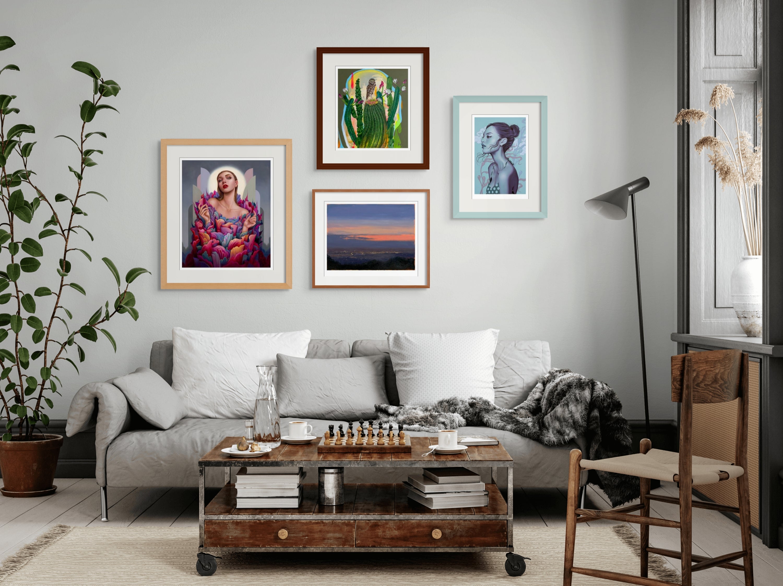 Cozy living room with a light gray sofa, a wooden coffee table featuring a chessboard, and five framed artworks on the wall. A tall green plant and a floor lamp are nearby. Natural light filters in through a large window with drapes.