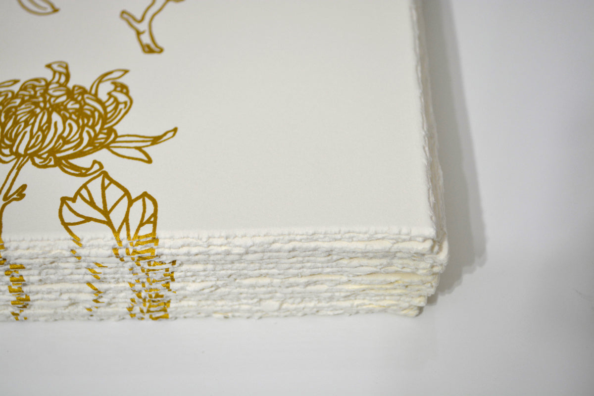 The Yellow Passerby & I by Tran Nguyen is a limited edition stack of white handmade paper with gold floral edge designs. It features rough, deckled edges for a textured artisanal look, ideal for adding a unique touch.