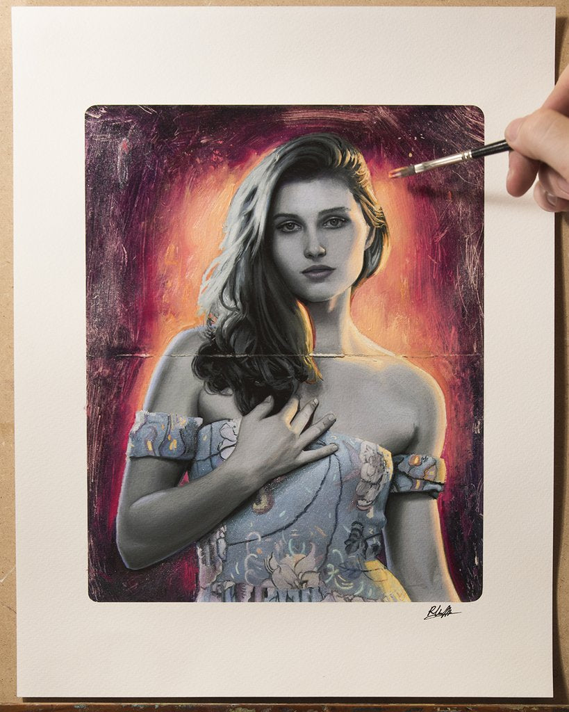 An artist is meticulously touching up a hyper-realistic painting titled Flare by Rod Luff. It depicts a woman with long hair in an off-shoulder dress, set against a warm orange and red background, each stroke hand embellished for depth.