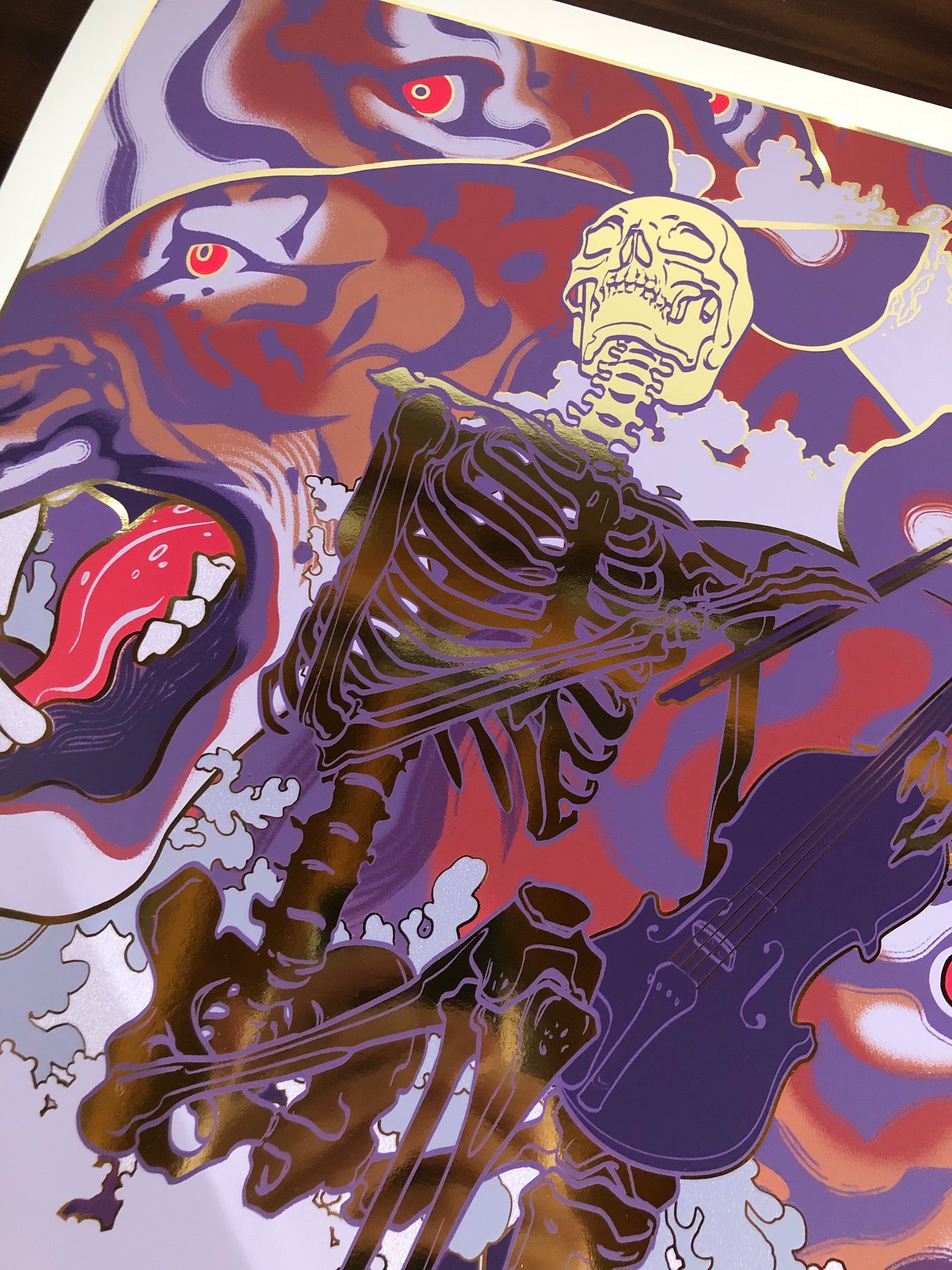 The Soothe screen print by JAW Cooper showcases a skeleton violinist against a swirling backdrop of purple, red, and pink. Abstract faces and eyes emerge from the colors, creating a surreal yet soothingly eerie atmosphere.