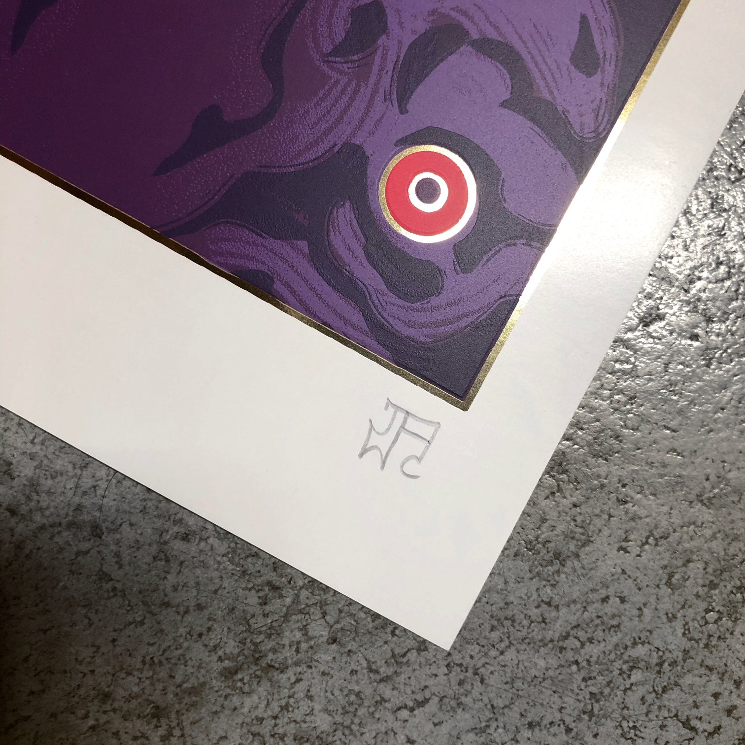 A close-up of JAW Coopers Soothe screen print displays a purple and black abstract design with a calming red and white circle. The art piece, surrounded by a white border, includes initials on the concrete surface.