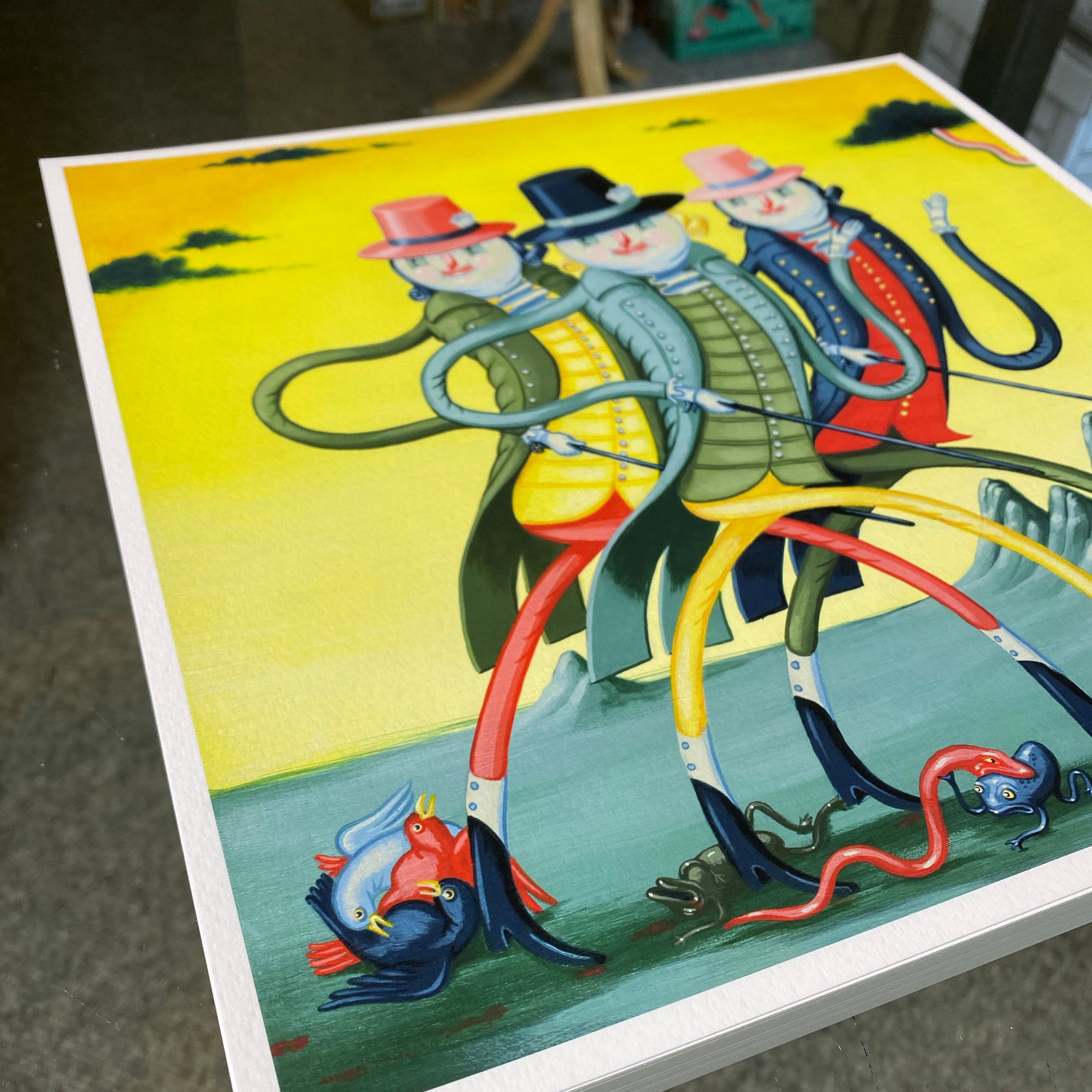 The Fancy Magicians by Travis Lampe is a captivating archival pigment print featuring three surreal, elongated figures with hats walking against a yellow background. Their snake-like intertwined legs and a small abstract creature near their feet add charm to this colorful artwork.