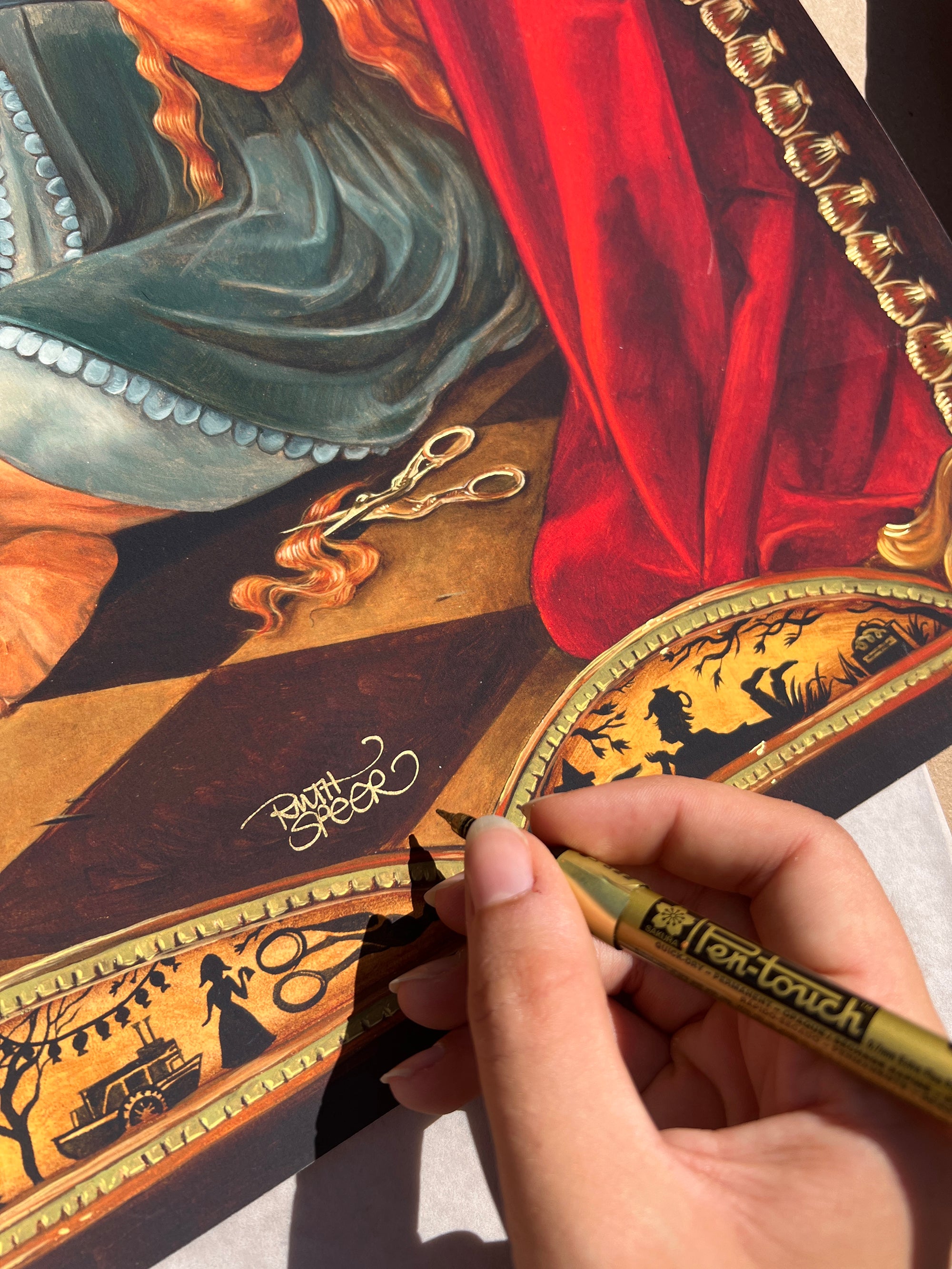 A hand skillfully uses a gold pen to recreate Portrait of the Unknown by Ruth Speer, outlining a detailed illustration with elements like a red curtain, scissors, and ornate border designs. Shadows from the hand play delicately on the paper.
