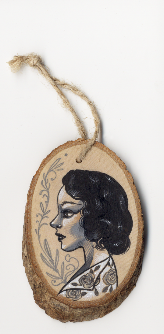 The Sandi Calistro Untitled #4 ornament features an acrylic painting of a womans profile with dark hair and floral tattoos, decorative floral elements, and includes a twine loop for hanging.