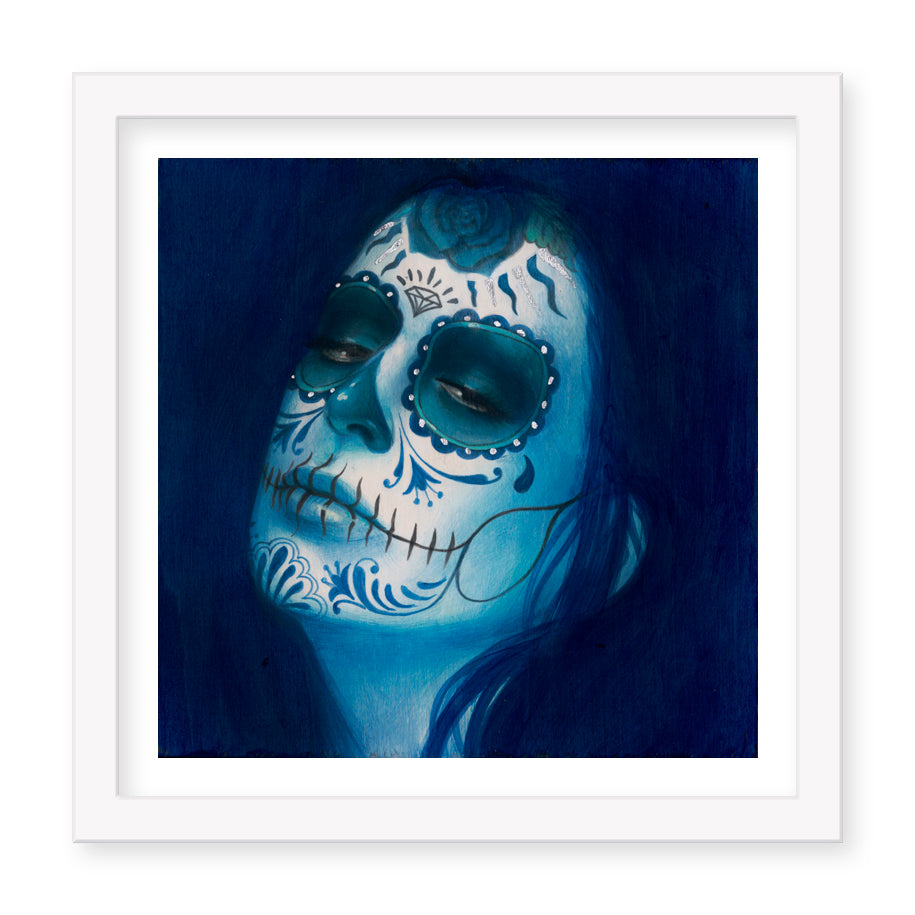 The Calavera Azul Añil (Artists Proof) by Sylvia Ji features a figure with closed eyes in blue hues, embellished with intricate sugar skull designs of floral and swirl patterns on a deep blue background, capturing the essence of Dia de los Muertos.