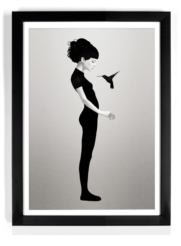 The limited edition fine art giclee print Let You Be by Ruben Ireland features a grayscale silhouette of a barefoot woman with her hair in a bun, standing in profile as a hummingbird hovers near her hands, framed with a black border.