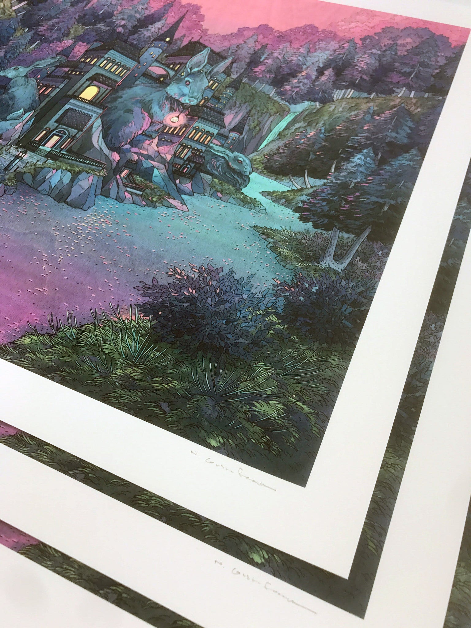 Warren," a limited edition print by Nicole Gustafsson, features a whimsical castle beneath a vibrant purple and pink sky. Several signed prints are stacked slightly askew, showcasing the artist’s signature on each one.
