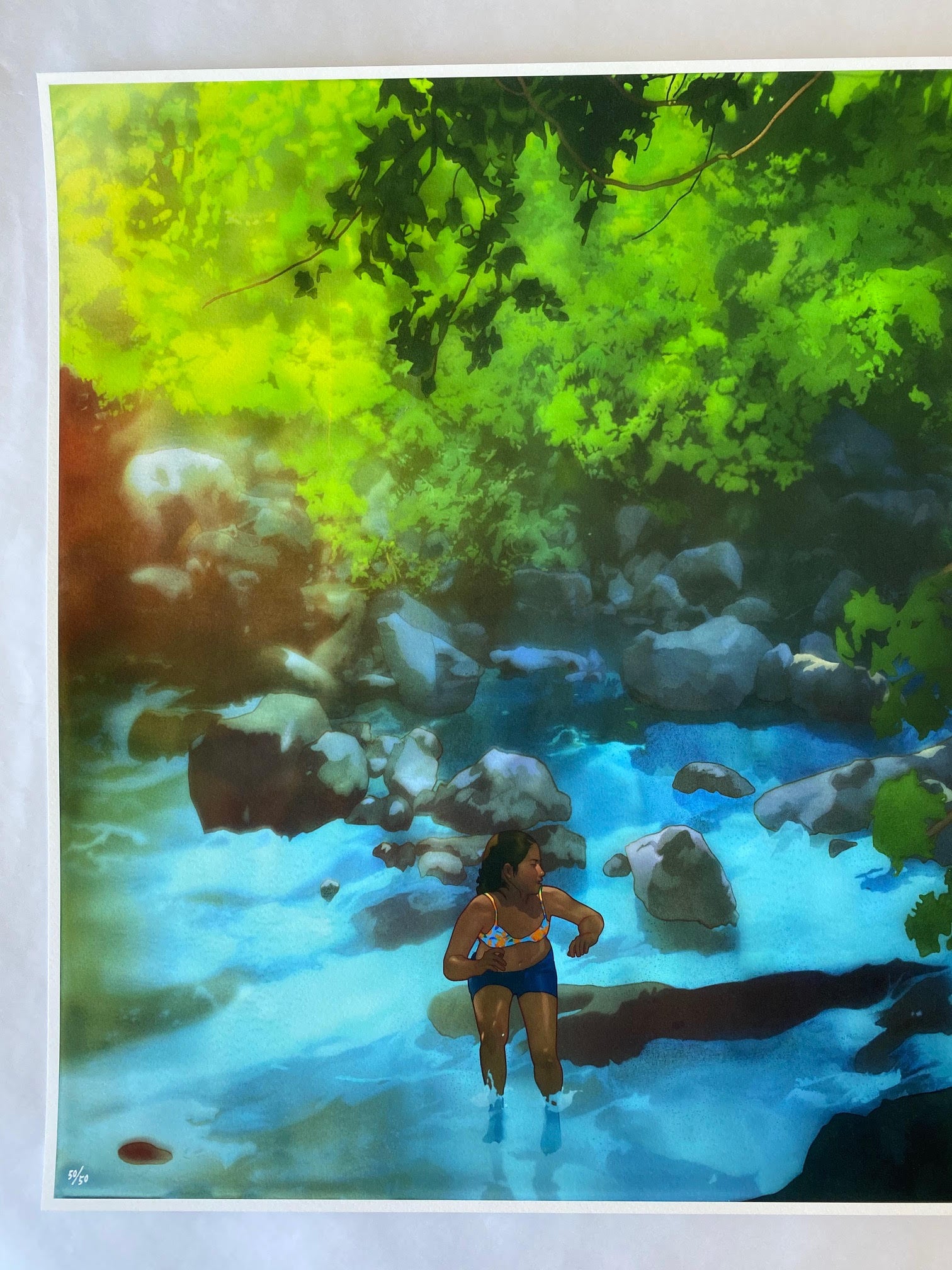 A person in a blue swimsuit wades through a sunlit, rocky stream beneath vibrant trees casting dappled light, evoking the serene beauty of nature captured in Edwin Ushiros limited edition print, You Have the Rest of Your Life to Figure Out the Consequences...