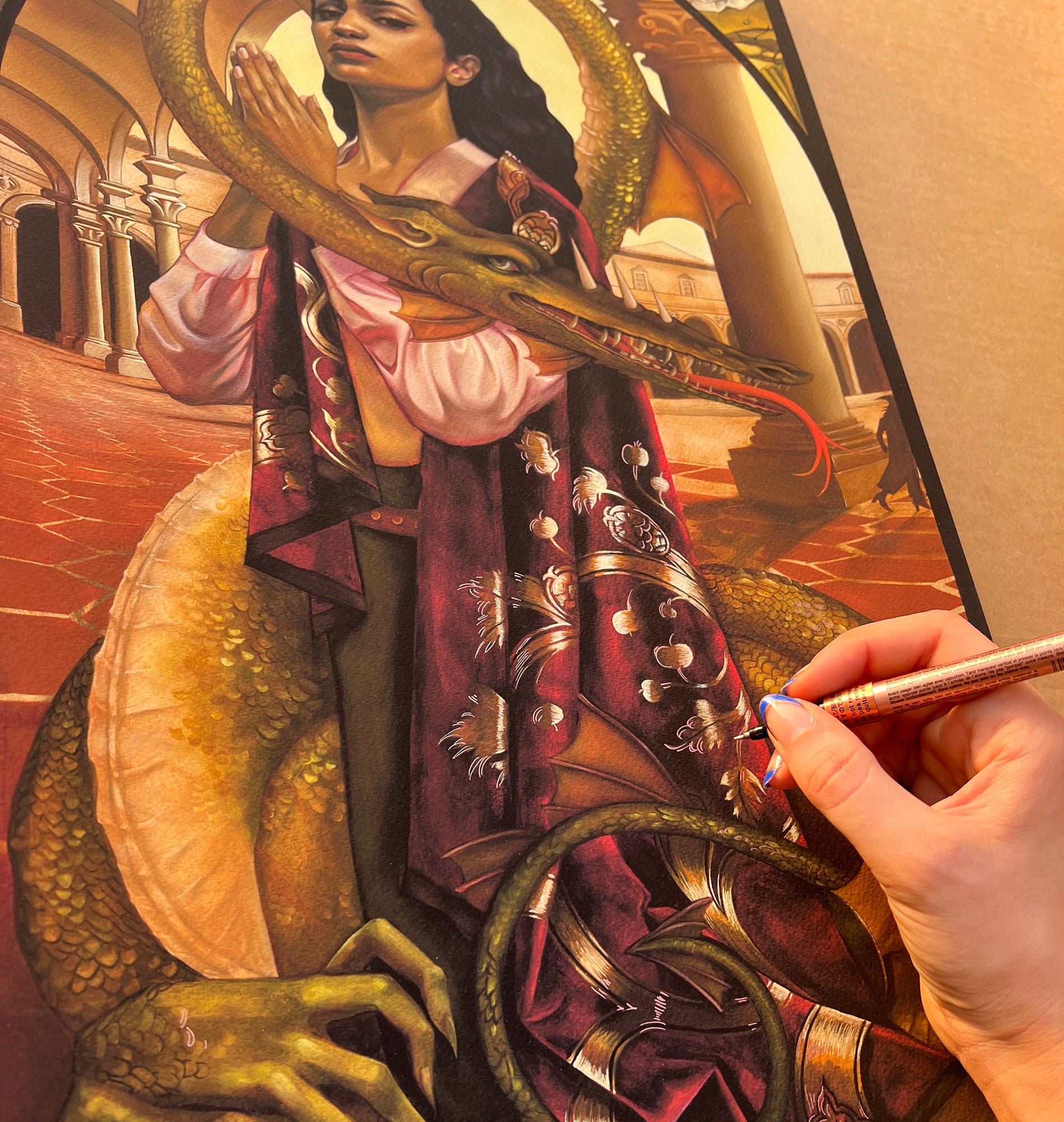 A hand colors the St. George & The Dragon by Ruth Speer, showing a figure like St. George in a patterned cloak with a gold dragon, set against ornate architecture with arches, crafted as an archival pigment print masterpiece.
