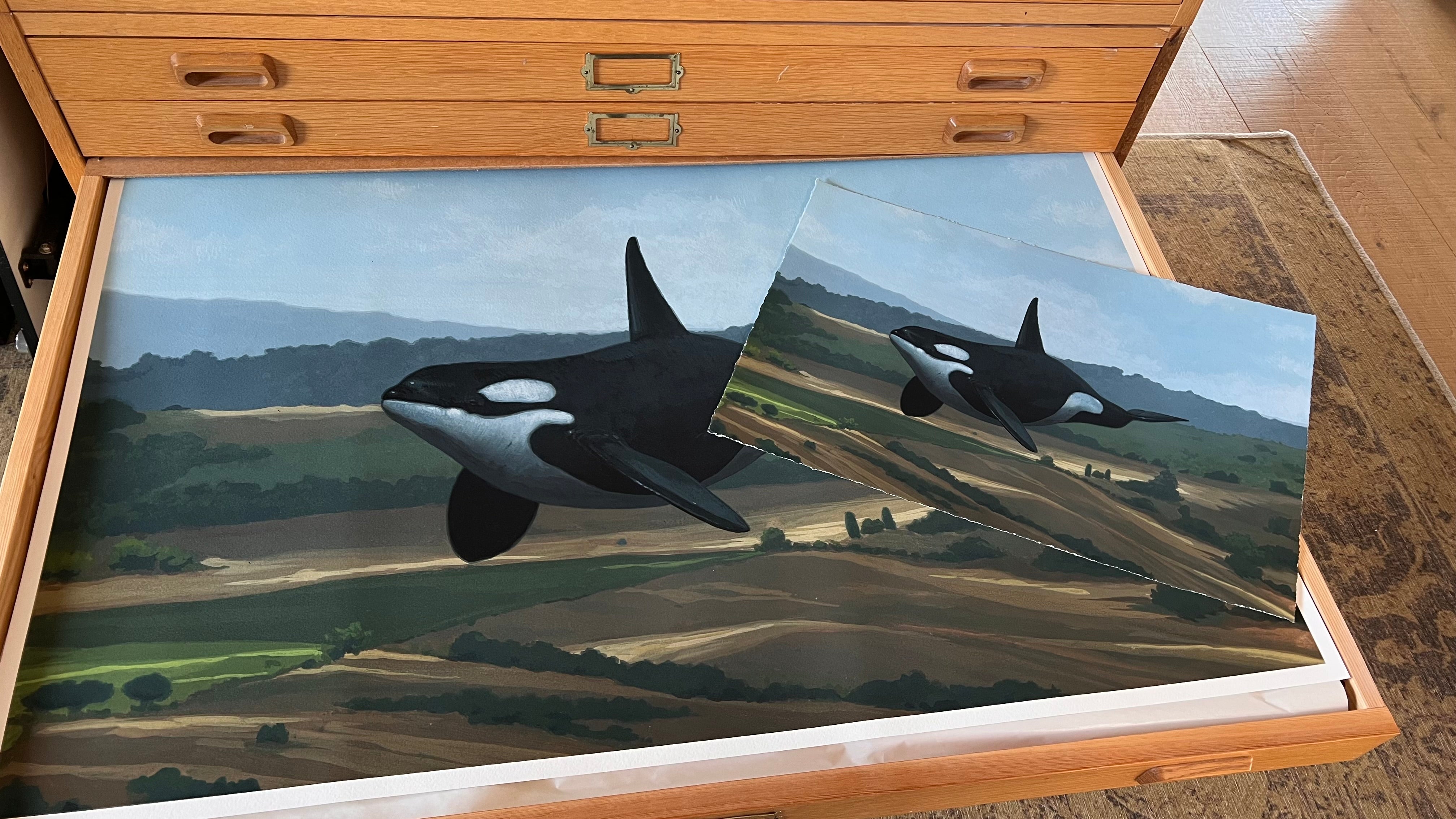 A wooden drawer holds Chris Austin's "Get On With It"—a large painting of an orca above a green-brown landscape—with a hand-embellished archival pigment print of the same artwork resting on top.