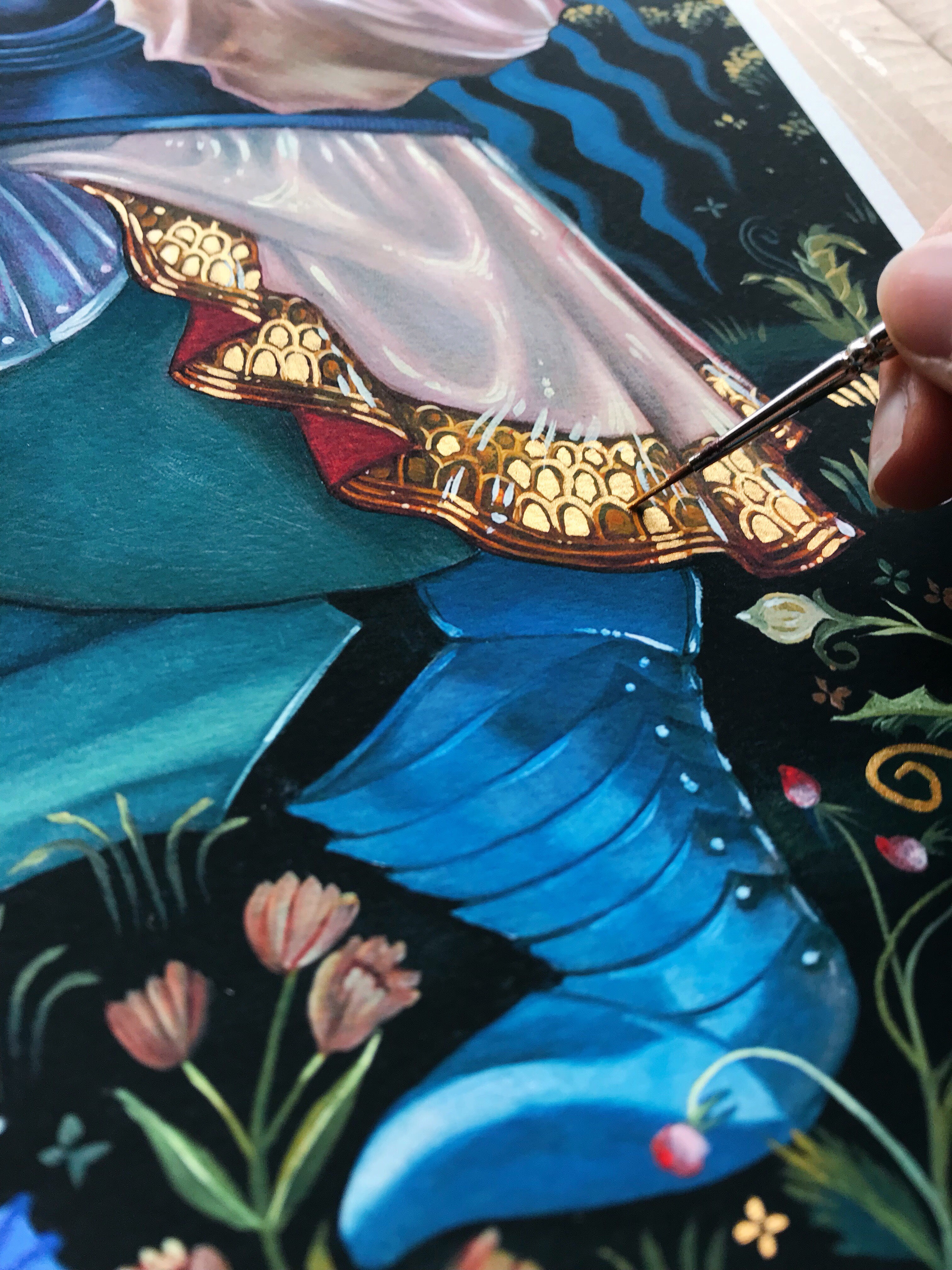 A hand with a brush adds intricate details to Valley of the Shadow by Ruth Speer, featuring a figure in blue with golden embroidery against a floral backdrop and wavy blue pattern for an exquisite Hand Embellished Edition.