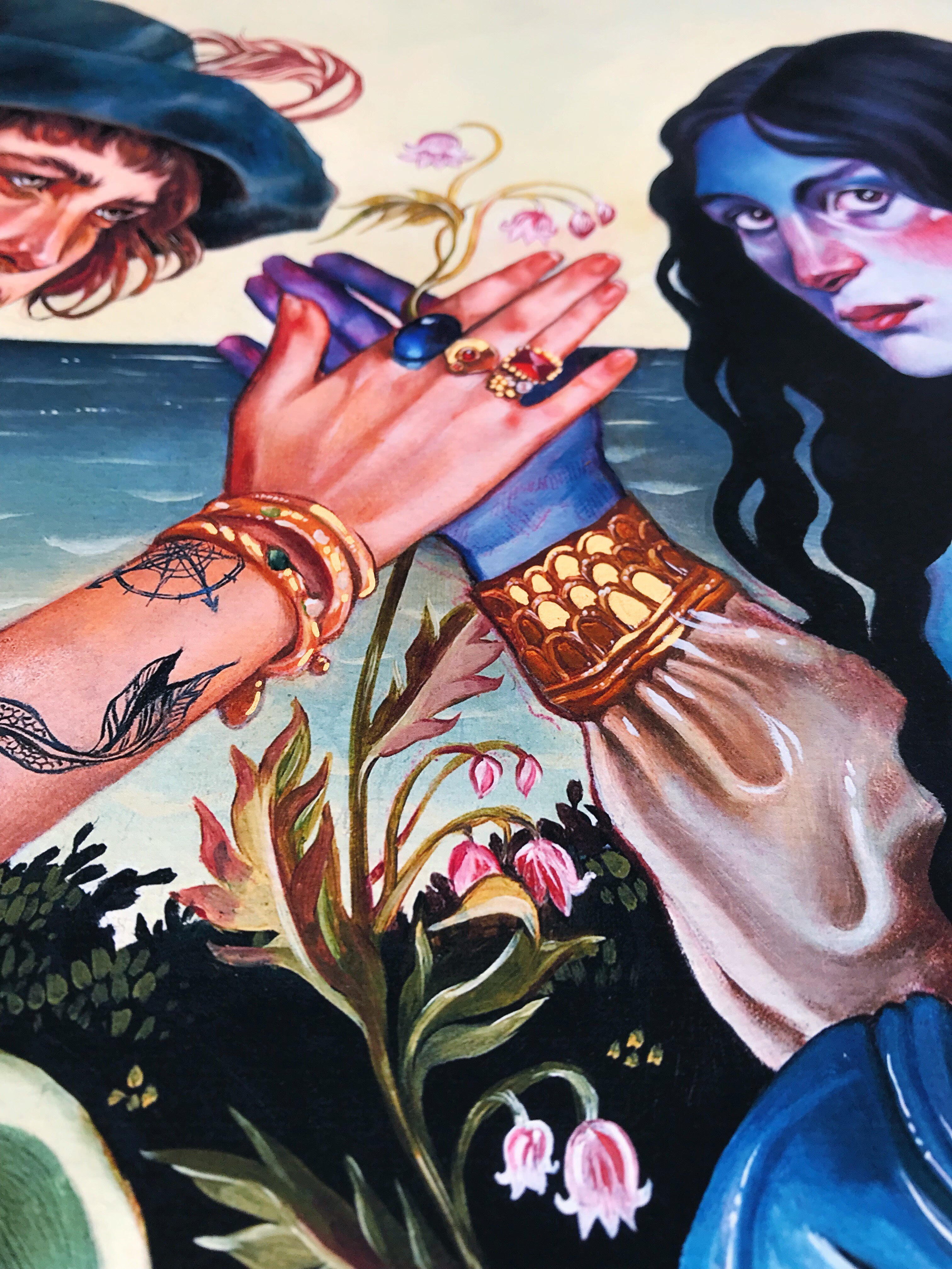 In Ruth Speers Archival Pigment Print Valley of the Shadow, two figures in vibrant clothing, with one bearing a tattoo, hold hands against a natural backdrop. They are adorned with colorful rings and bracelets, surrounded by delicate pink flowers leading to distant water.