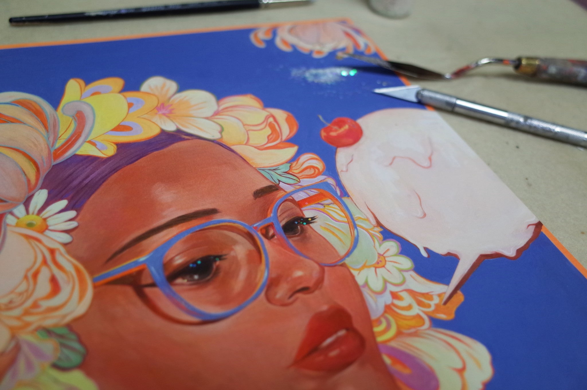 Sweetness #2 by Helice Wen features a vibrant portrait of a person with glasses amidst colorful flowers and a white bird with a red head. Art tools and brushes accompany the signed, numbered edition, possibly hand embellished for depth.