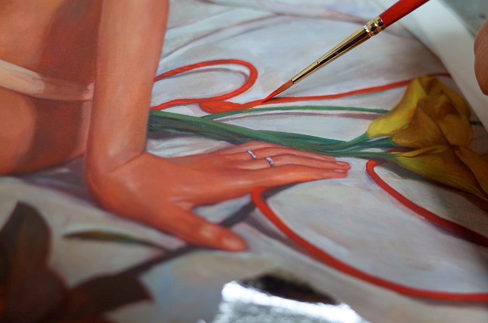 A hand decorates Little Minimal Melody #2, an archival pigment print by Helice Wen, using a fine brush on artwork featuring a yellow flower with red flowlines. Each stroke adds artistry, while a silver ring enhances the persons creative process.