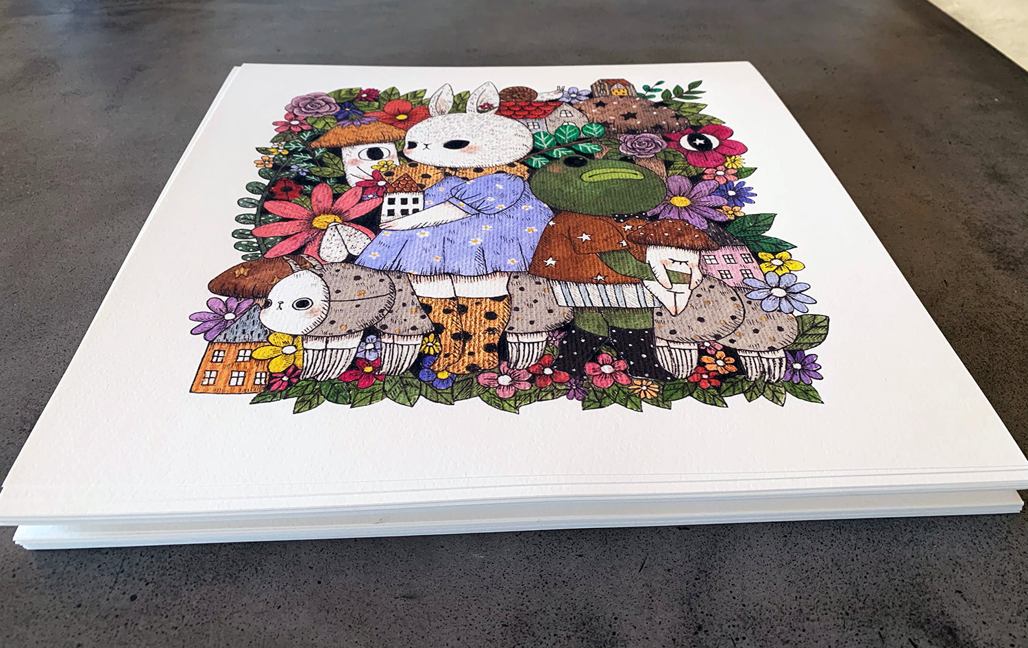 The Gala by jb0xtchi is a limited edition illustrated print featuring whimsical animals and flowers, with a rabbit in a blue dress holding a house, surrounded by frogs, mushroom characters, and ladybugs. Each archival pigment print is signed and numbered for authenticity.