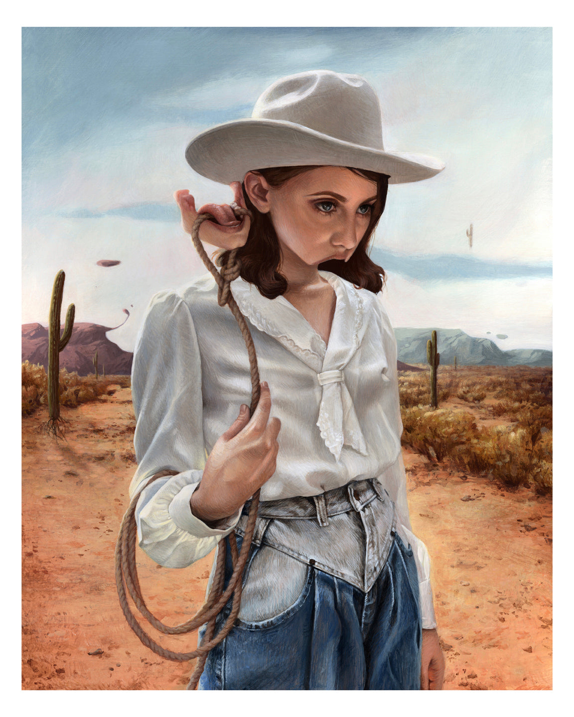 In Meagan Magpie Rodgers archival pigment print Alone With My Thoughts, a young person in a cowboy hat and white shirt stands thoughtfully in a desert with cacti, mountains, and clouds, loosely holding a rope over one shoulder, evoking solitude.