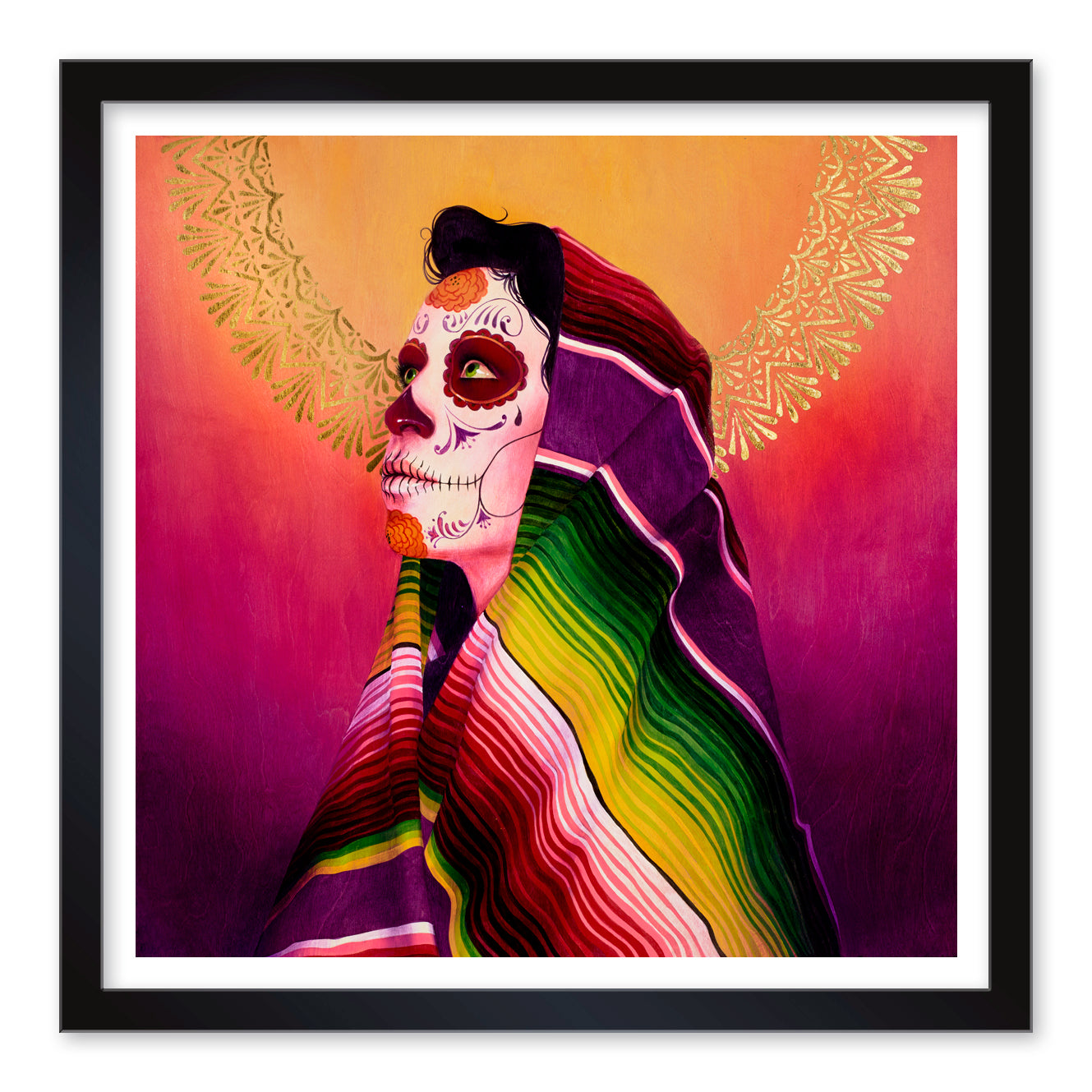 A person with sugar skull makeup, wrapped in a vibrant Serape Morado, gazes upwards against a warm gradient. A decorative golden halo encircles their head. This stunning piece by Sylvia Ji is available as limited edition prints, elegantly framed in black.