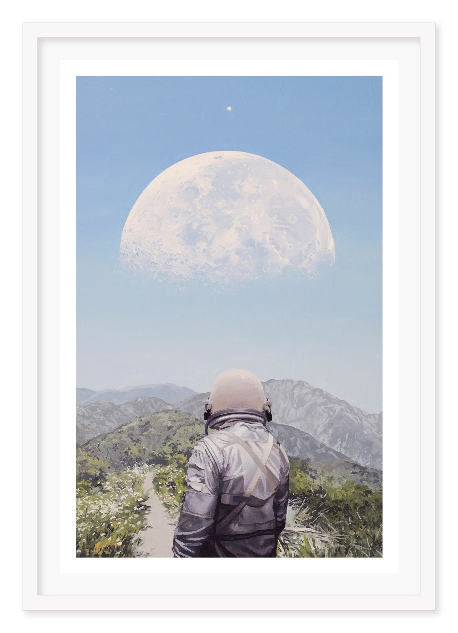 A person in a jacket and helmet stands on a mountain path under the serene blue sky, gazing at the White Moon by Scott Listfield. Lush green hills and distant mountains add to this surreal landscape.